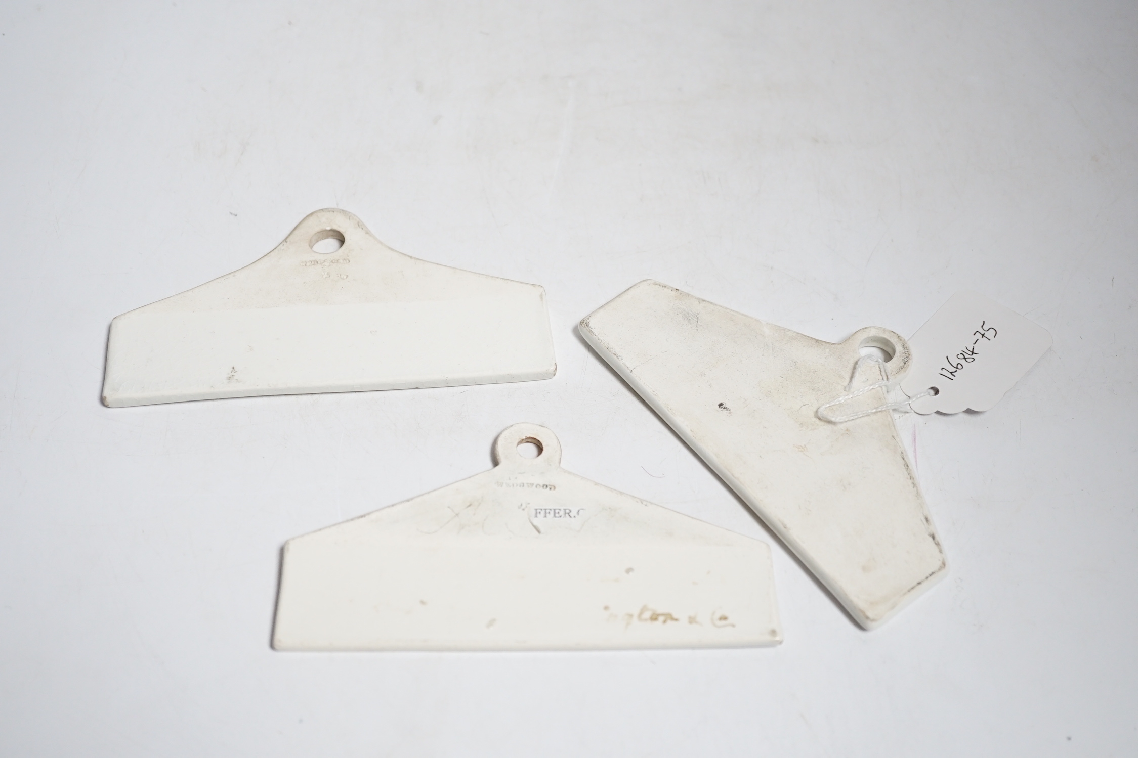Three late 18th century creamware cellar labels, two claret stamped Wedgwood and one sherry, unmarked, 14 cms wide.